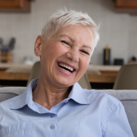 Senior woman sitting at home laughing