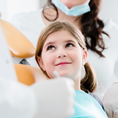 Little girl looking up at dentist and smiling