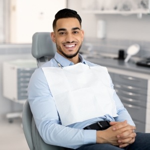 Man sitting in dental chair with hands folded