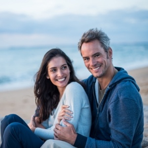 Man and woman sitting on a beach smiling