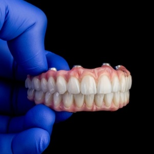 Gloved hands holding dentures meant for dental implants