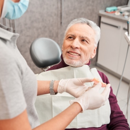 Dentist showing male dental patient dentures