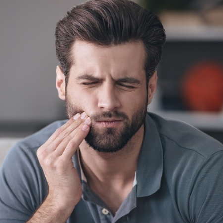 Bearded man rubbing jaw in need of emergency dentist in Port Orange