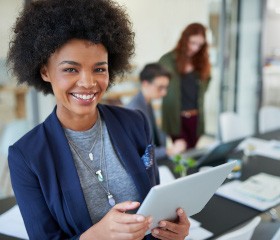 Woman smiling while holding tablet in office