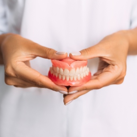 Close-up of hands holding full dentures