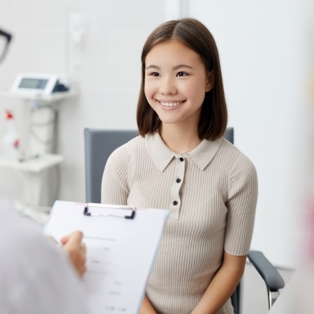Young woman smiling at dentist while they fill out a form