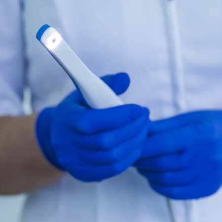 Gloved hands holding an intraoral camera