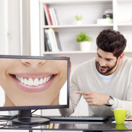 Man sitting at desk with computer monitor with smile