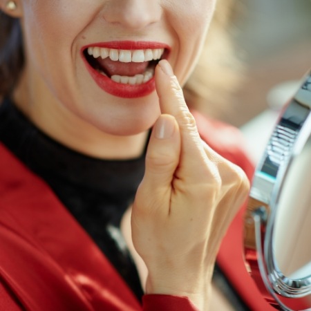 Woman checking smile in mirror after veneers